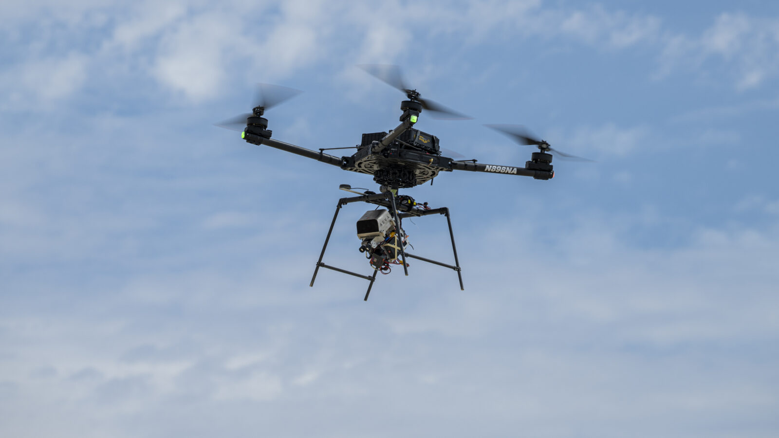 A remotely piloted drone with four rotors carries a guidance and navigation experiment through flight maneuvers.