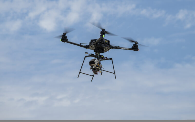A remotely piloted drone with four rotors carries a guidance and navigation experiment through flight maneuvers.