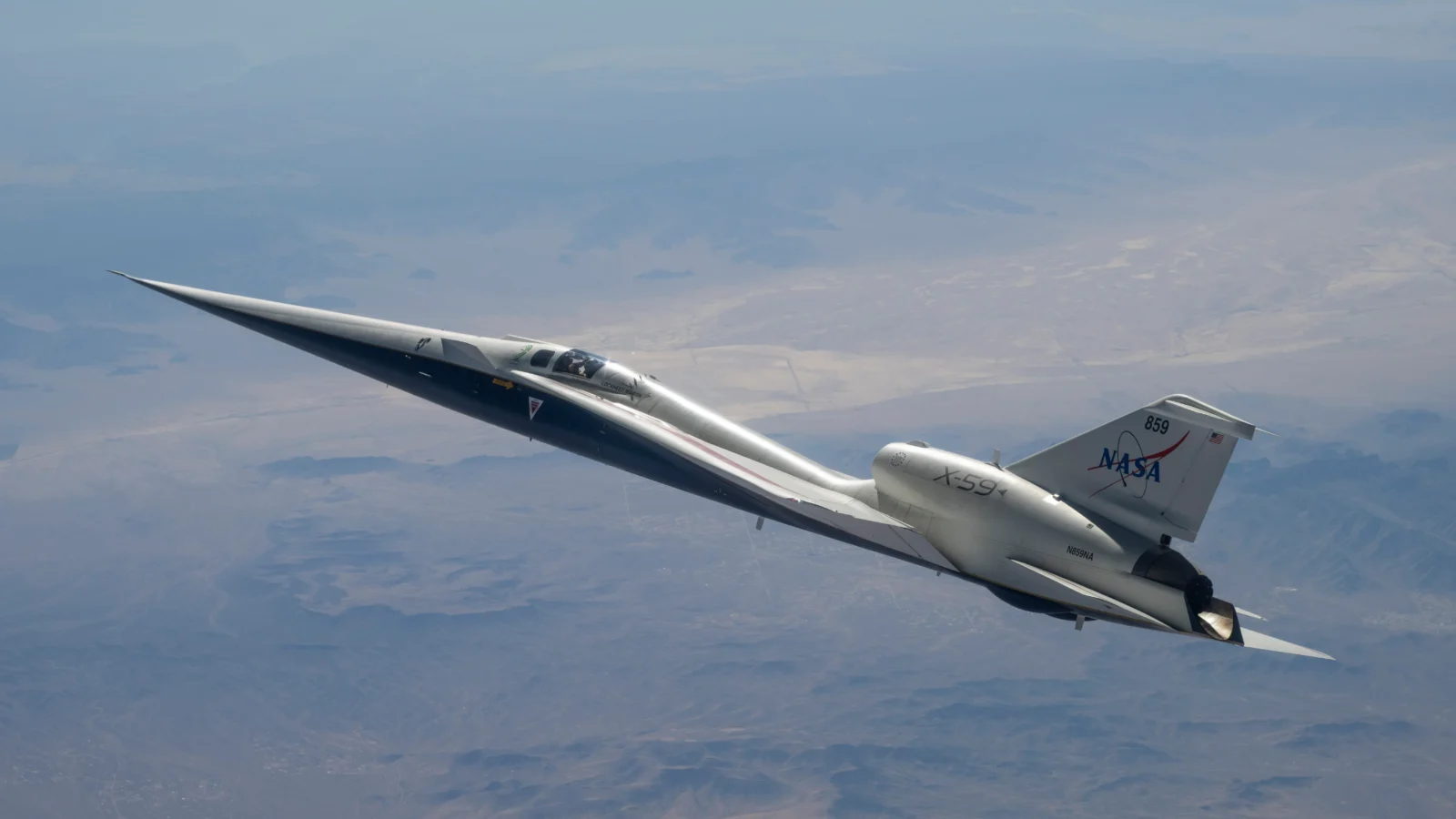 NASA’s white and blue X-59 quiet supersonic research aircraft is shown in profile against a blue sky during a test flight on June 10, 2026.