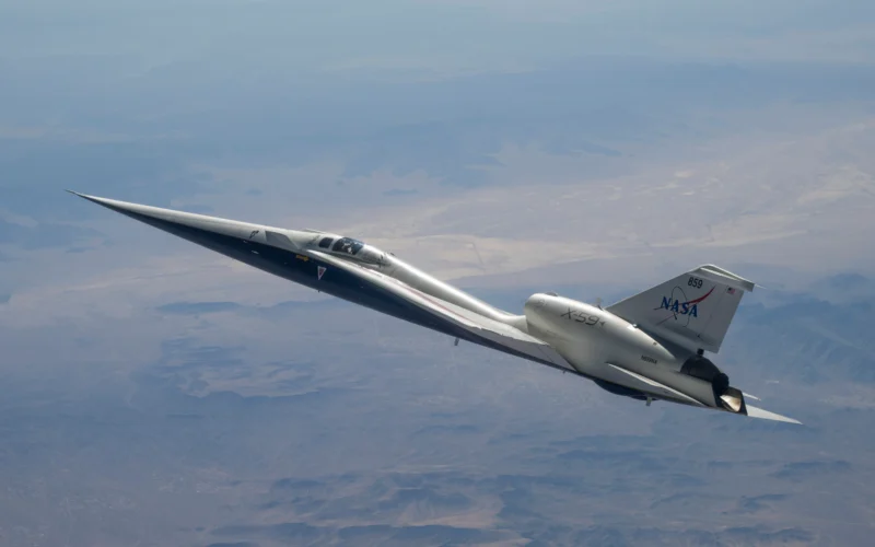 NASA’s white and blue X-59 quiet supersonic research aircraft is shown in profile against a blue sky during a test flight on June 10, 2026.